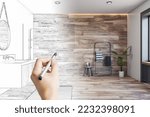 Human hand with pencil making design project of modern bathroom with stylish shower area, towel holder and green plant on wood effect tiles wall background