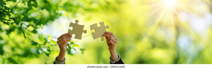 Human hand with piece of jigsaw outdoors on the nature background. Concept of the teamwork and togetherness