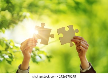 Human Hand With Piece Of Jigsaw Outdoors On The Nature Background. Concept Of The Teamwork And Togetherness