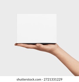 Human hand presenting a generic plain white unbranded square box, ready for custom branding or showcasing a new product, gift, or delivery concept against a clean light background