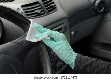 Human hand in protective gloves  cleaning inside car steering wheel using antibacterial or cleaning solution and wet wipes