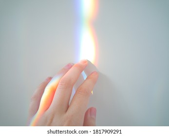 Human hand reaching into a colorful rainbow on a white wall. LGBTQ concepts. - Powered by Shutterstock