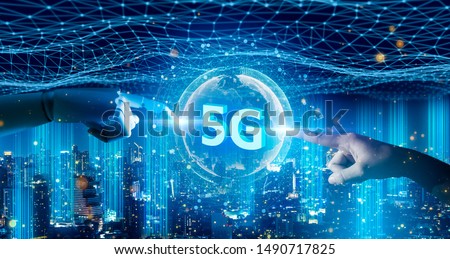 Human hand and robot android hand pointing at icon 5g and digital world.5G network digital hologram and internet of things on city background.5G network wireless systems concept.