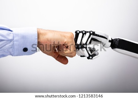 Human Hand And Robot Making Fist Bump On Gray Background