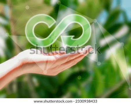 Human hand showing Arrow Infinity symbol with two globes of different colors, circular economy Endless and unlimited for future business growth and design for reuse and environmental sustainability.