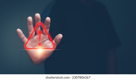 Human hand showing red triangle caution warning sign for maintenance notification error and risk concept.