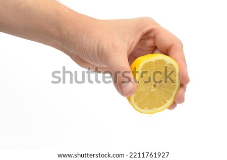 human hand squeezing lemon large pan on white background