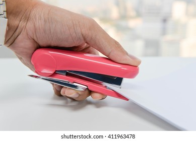 Human Hand Is Stapling The Paper With Pink Stapler