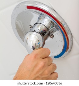 Human Hand switches a Shower faucet cold and hot water in the bathroom