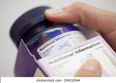 Human Hand Take Out Bottle With Vitamin Pills From The Box For Reading Nutritional Information.