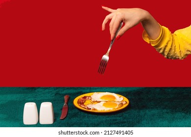 Human hand tasting bacon and eggs isolated on green and red background. Vintage, retro style interior. Food pop art photography. Complementary colors, Copy space for ad, text