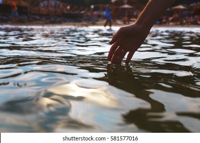 Human Hand Touching Sea Water.