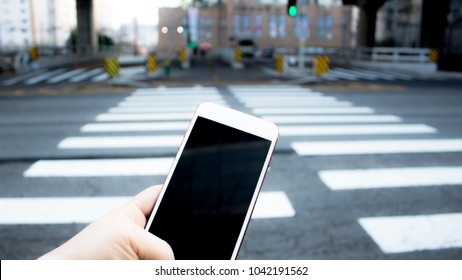 Human hand using smartphone at crosswalk when cross sign. Unsafe behavior. Dangerous situation. Public campaign. - Powered by Shutterstock