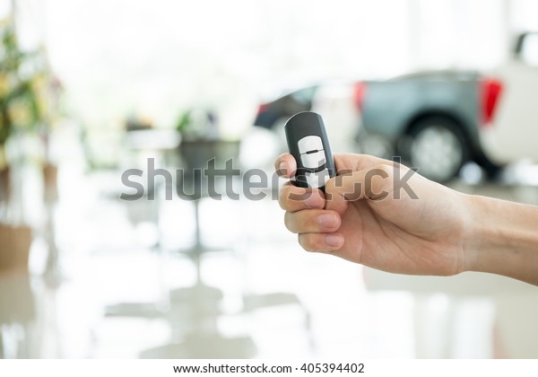 Human hands giving thumbs up with car key in\
car shoowroom