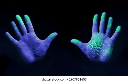 Human Hands Glowing From UV Ultra Violet Light Showing Bacteria And Viruses On A Black Background, Showing The Importance Of Hand Washing.