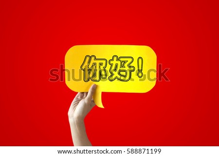 Human Hands Holding 'Nihao' Yellow Speech Bubble Over Red Background - Nihao means Hello in Chinese - Chinese learning concept