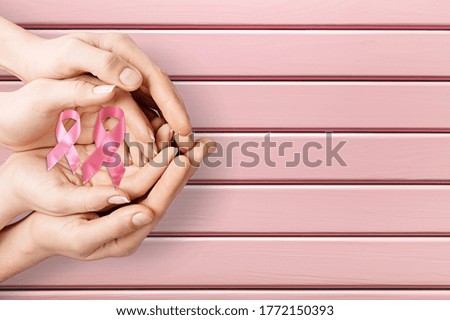 Human hands holding pink ribbons, breast cancer awareness