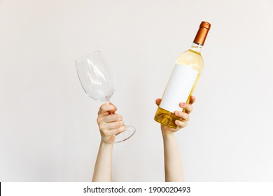 Human Hands Holding A Wine Glass And Bottle Of White Wine On Wall Background.