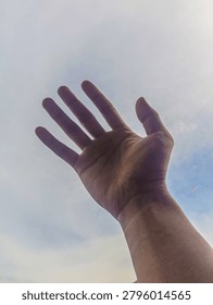 Human hands open and ready to help against the background of clean sky and white clouds.