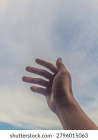 Human hands open and ready to help against the background of a clean sky and white clouds.