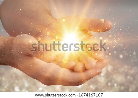 Human hands praying for blessing with lights shining