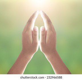 Human hands praying over blurred nature background