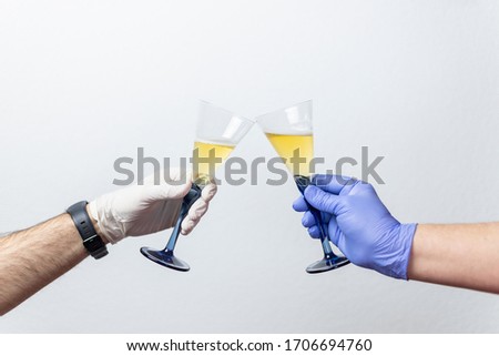 human hands with protective gloves toast with two cups. Concept of the end of the coronavirus crisis, covid 19
