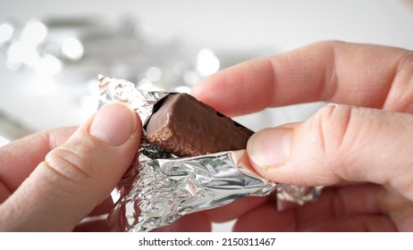 Human Hands Taking And Unwrapping Silver Candy