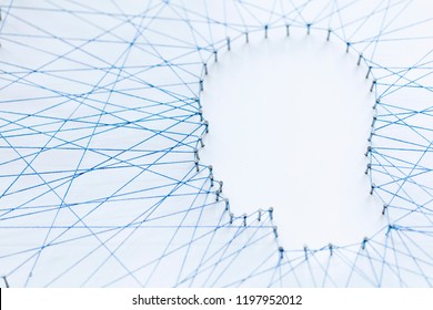 Human head shape made from a large grid of pins connected with string. Communication technology and mental health concept
