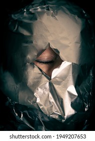 Human Head Is Wrapped With Aluminium Foil. Only The Right Eye Is Visible. It Is Closed. Black Background