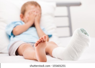 Human Healthcare And Medicine Concept - Little Child Boy With Plaster Bandage On Leg Heel Fracture Or Broken Foot Bone