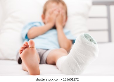 Human Healthcare And Medicine Concept - Little Child Boy With Plaster Bandage On Leg Heel Fracture Or Broken Foot Bone