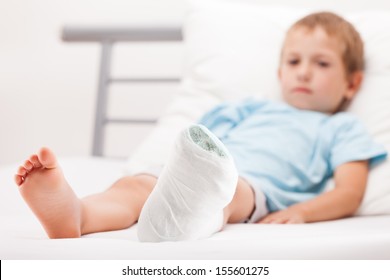 Human Healthcare And Medicine Concept - Little Child Boy With Plaster Bandage On Leg Heel Fracture Or Broken Foot Bone