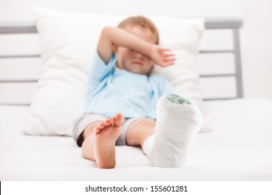 Human Healthcare And Medicine Concept - Little Child Boy With Plaster Bandage On Leg Heel Fracture Or Broken Foot Bone