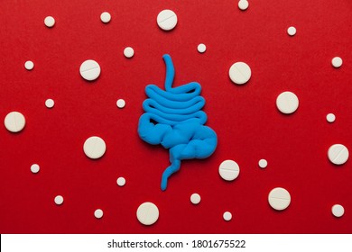 Human Intestines With Pills On Red Background. Diarrhea And Constipation. Stitches And Stomach Discomfort.