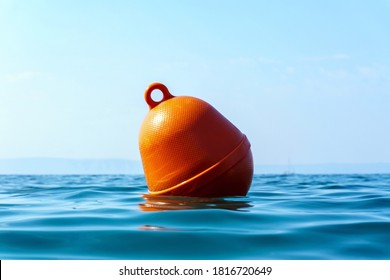Human life saving concept, SOS. Orange floating buoy in the waves of the Adriatic Sea. Selective focus, afternoon. Croatia, Europe.