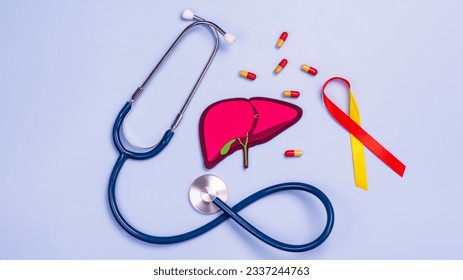 Human liver organ, stethoscope, yellow and red ribbon, pills. World hepatitis day. National liver health awareness month. Liver transplantation, donation background - Powered by Shutterstock