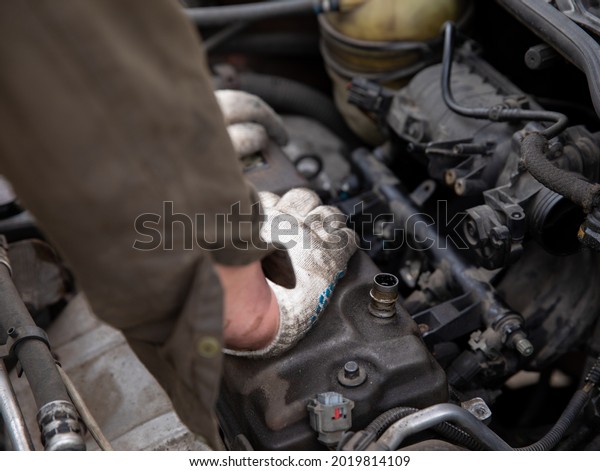 A human\
master repairs a car engine with\
gloves.