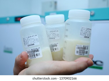 At The Human Milk Bank Laboratory. Lab Assistant's Hand Holding  Breast Milk Storage Containers With Human Milk Inside, Freezers On A Background