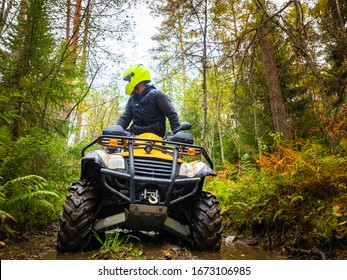 Human on the ATV. A man rides through the forest on a quad bike. Riding an ATV through mud. Off-road driving. Extreme sports. The ATV driver is looking back. Concept - a contest on quad bikes