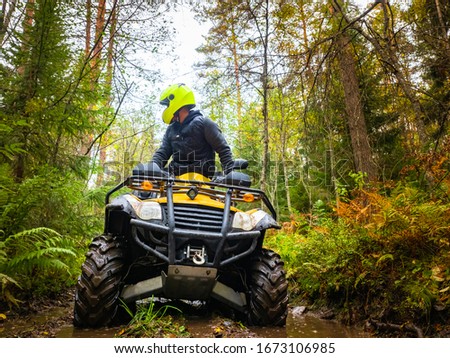 Human on the ATV. A man rides through the forest on a quad bike. Riding an ATV through mud. Off-road driving. Extreme sports. The ATV driver is looking back. Concept - a contest on quad bikes