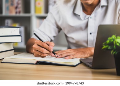 Human read books to increase knowledge. Student in glasses making notes writing down information from book in  library. Education learning concept with opening book or textbook in old library.