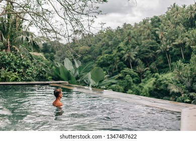 Human Relaxing In Bali Infinity Pool With Jungle View 