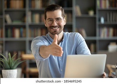 Human resource agent male recruiter sit at desk extends his hand to camera for handshake greeting applicant showing polite gesture start job interview in modern office. Welcoming, cooperation concept - Shutterstock ID 1854695245