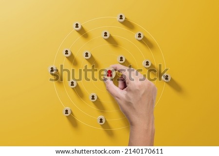 Human resource management and recruitment business concept. Hand holding wood cube with icon people on yellow background