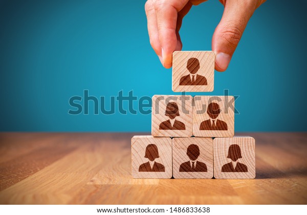 Human resources, corporate\
hierarchy concept and multilevel marketing - recruiter complete\
team represented by wooden cube by one leader person (CEO) and\
icon.
