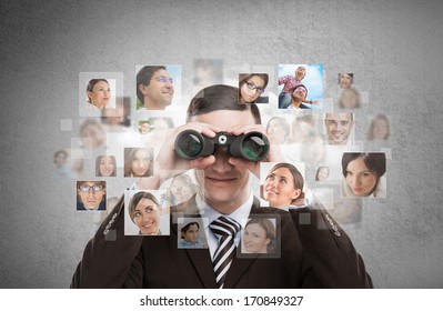 Human resources, CRM, assessment center and social media concept - business man looking for employees through binoculars. Lots of people portraits around him - Powered by Shutterstock