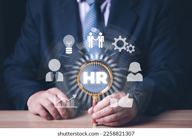 Human Resources HR management Recruitment Employment Headhunting Concept , businessman uses magnifying glass to search and select job applicantsThe process of selecting people to join the work. - Shutterstock ID 2258821307