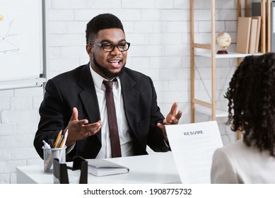 Human resources manager communicating with positive vacancy applicant on employment interview at office. HR specialist talking to job candidate, looking through CV