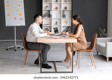 Human resources manager with laptop interviewing male applicant in office - Powered by Shutterstock